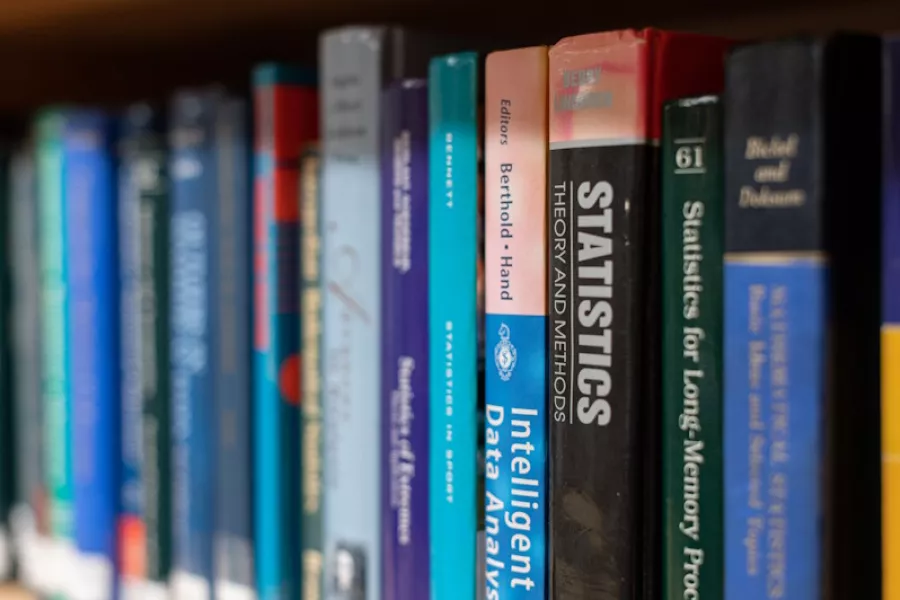 Books on a bookcase, focusing on the word Statistics on the spine.