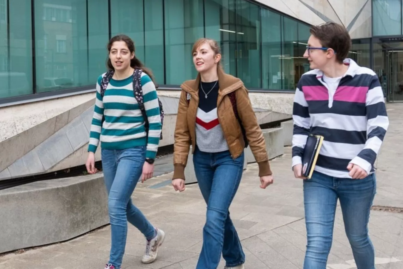 Three postgraduate students walking past an Oxford science building