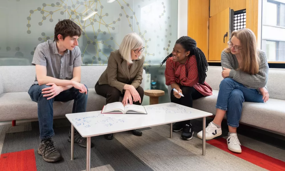 Students and tutor in discussions around a table.
