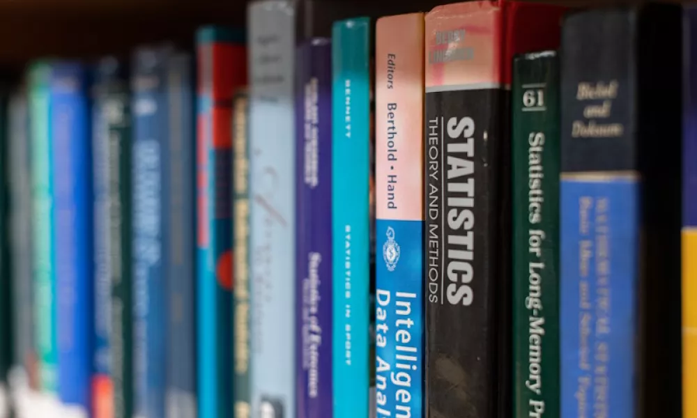 Books on a bookcase, focusing on the word Statistics on the spine.